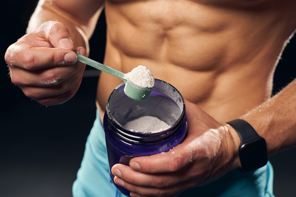 shirtless-muscly-man-wearing-sport-shorts-scooping-powder-protein-from-jar