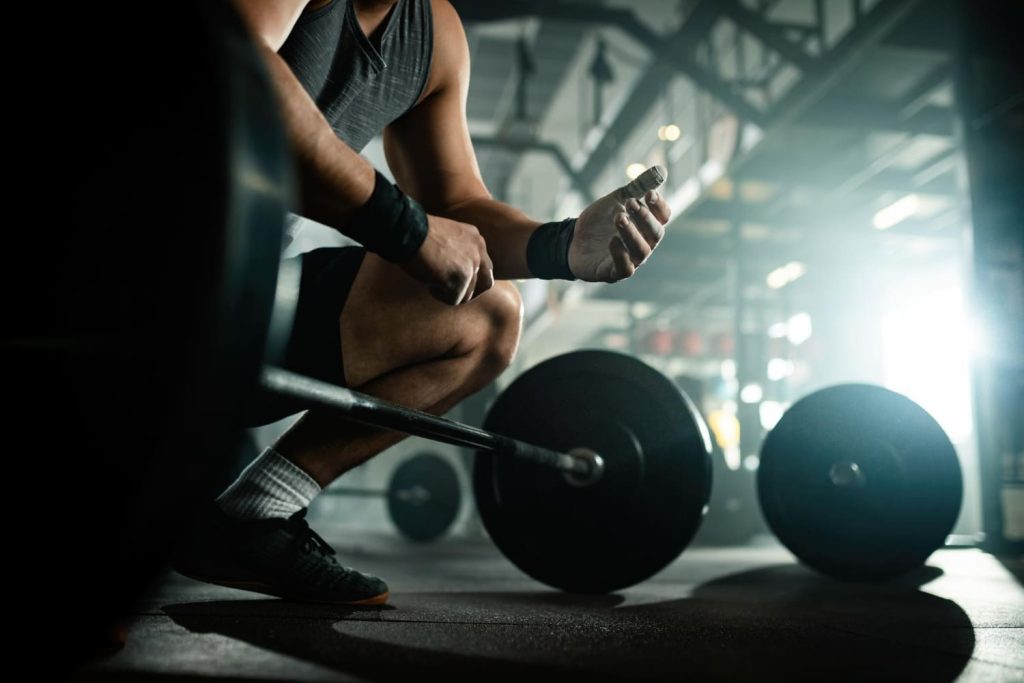 low-angle-view-unrecognizable-muscular-build-man-preparing-lifting-barbell-health-club