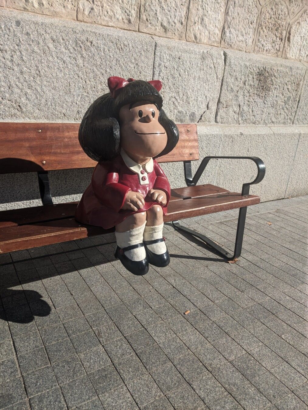 Figura 3D de Mafalda sentada en un banco al sol