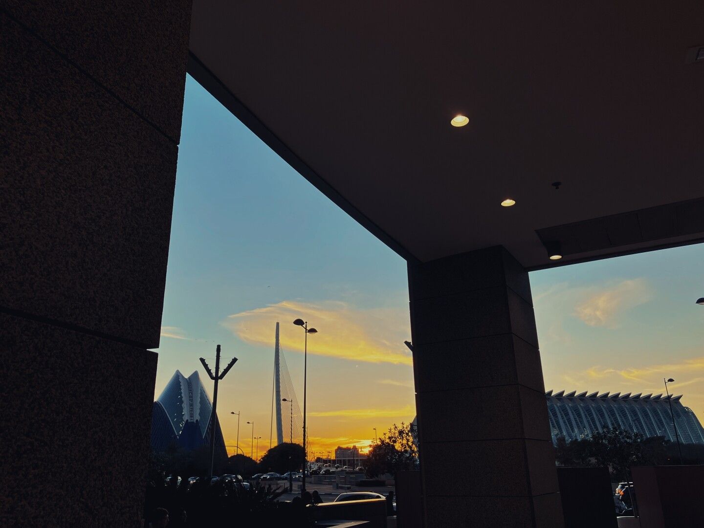 Unos ventanales y al fondo un cielo anaranjado y la ciudad de las artes y las ciencias al fondo.