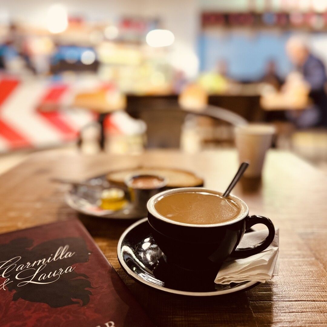 Bodegón de desayuno con mi libro, un café con leche fría más rico que pa qué y una tostada de tomate y aceite, hoy, en pan blanco.