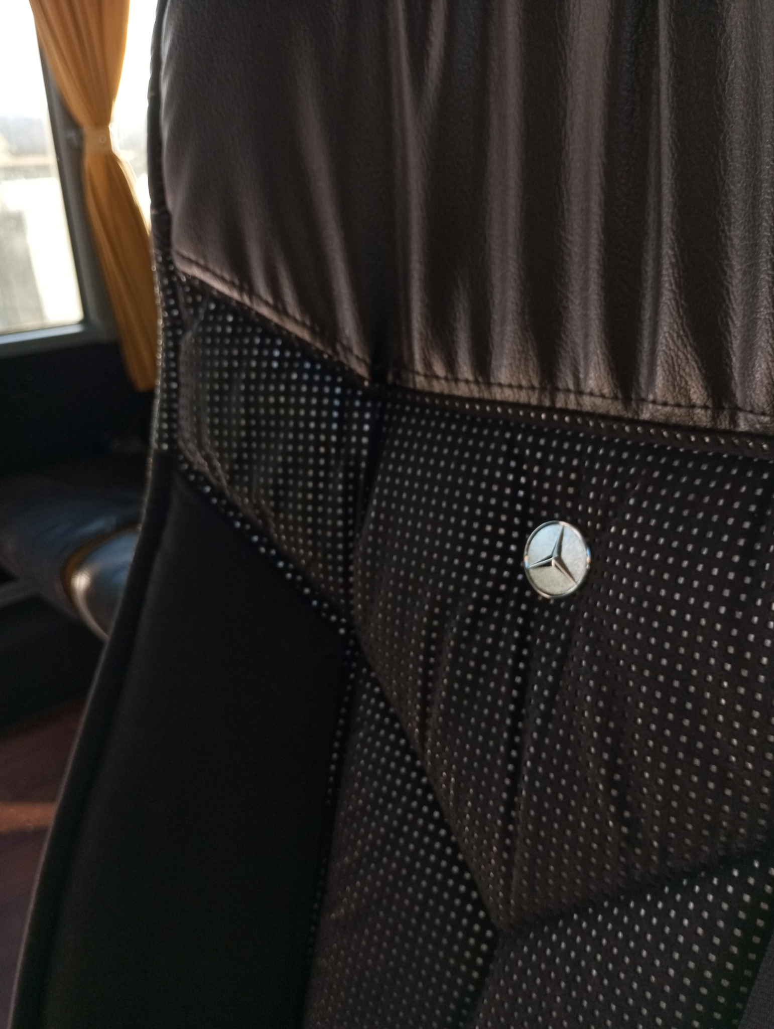 Asiento del bus de cerca, acolchado y con la insignia de Mercedes también